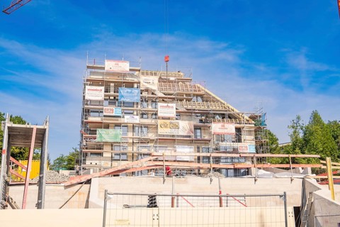 Building under construction with scaffolding and advertising banners under blue sky, carpentry, new