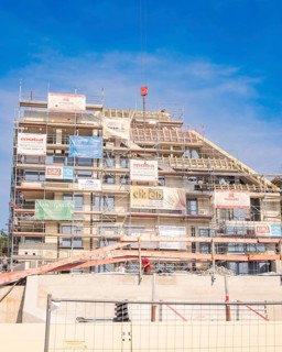 Large building under construction with scaffolding and various advertising banners as well as