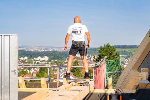 A construction worker on a roof with a view of the urban landscape under bright sky, carpentry, new