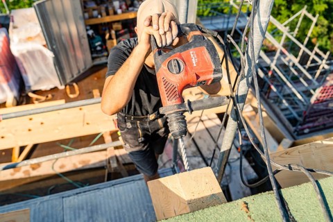 A construction worker uses a drill to work on wood in a construction project, carpentry, new