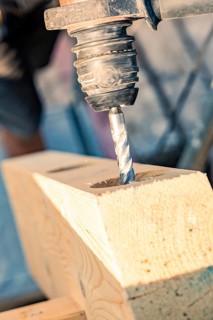 A close-up of a drill drilling a hole in a wooden beam, carpentry, new building, Stuttgart, Germany