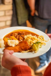 Plate with goulash and other garnishes carried by one person at a meal