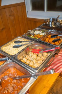Buffet with various dishes and serving tongs on a table