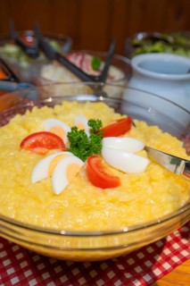 Potato salad with tomato and egg slices on a table decorated with checkered cloth