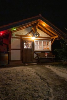 Small wooden hut decorated at night with festive lights and winter accessories