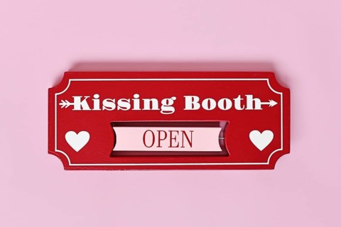Valentine's Day kissing booth sign with hearts on pink background. Romantic love concept flat lay