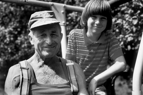 Farmer and his young assistant on the tractor, on a former Franconian farm, black and white,