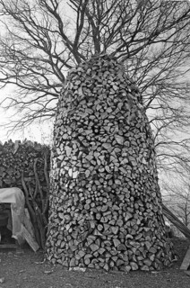 Polished firewood for a pyramid, on a former Franconian farm, black and white, Bavaria, Germany
