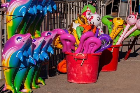 Red plastic buckets with colorful balloons in unusual shapes including cats etc, and dolphins in a