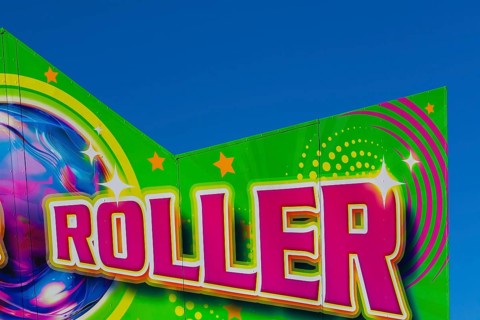 Close-up of the word Roller painted in purple fluorescent paint on banner at Fun Show traveling