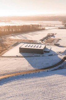 Warehouse in snowy landscape with surrounding roads and forests at sunset, Nagold, Calw district,