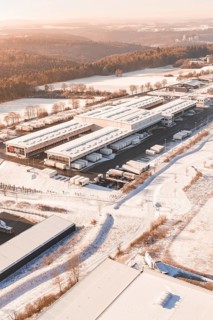 Warehouse with surrounding trucks in snow-covered landscape at morning sun, Nagold, Calw district,