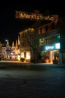 Festively illuminated city street at night with decorated entrance and historic buildings, Nagold,