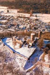 A snowy castle with medieval towers looking over a village of small houses, Nagold, Calw district,