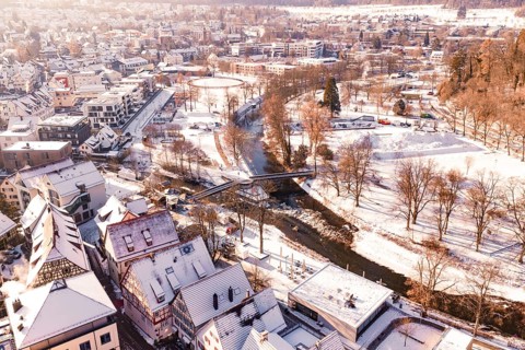 Snowy town with a river and a bridge, surrounded by trees and houses, Nagold, Calw district, Black
