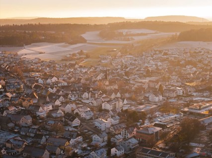 City view in golden light, snowy roofs and wintry hills in the background, Althengstett, Calw