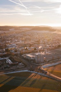Urban panorama at sunset, pastel colors in the sky, surrounded by fields and snow-covered areas,