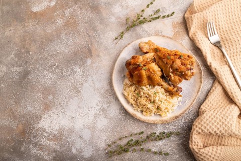 Fried Turkey Wing with spices and rice on brown concrete background and linen textile. top view,