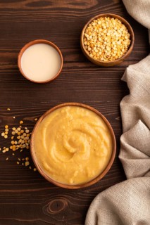 Pea cream soup, Puree, porridge in wooden bowl on wooden background and linen textile. Diet,