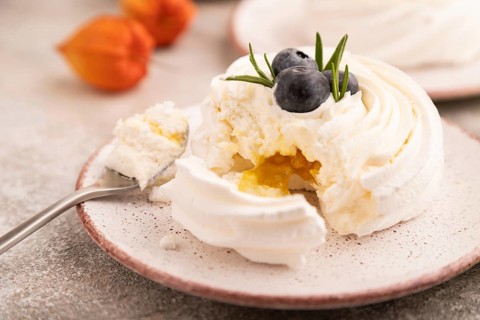 Pavlova Meringue dessert with crisp meringue and blueberry, cup of coffee, on brown concrete