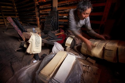 A Tibetan prints the pages of sacred religious texts at the historic Tibetan Buddhist printing