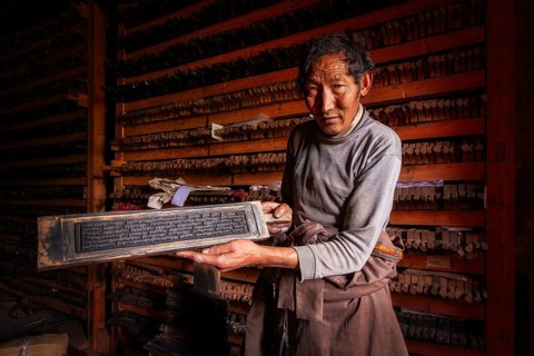 A Tibetan shows the printing block for sacred religious texts at the historic Tibetan Buddhist