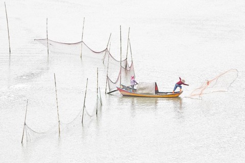 Woman and man in a small boat fishing with a net in Xiapu, Fujian Province, along the East China