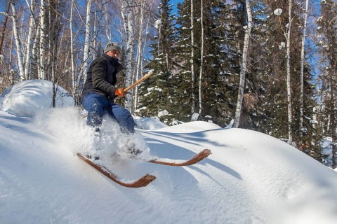 Skier with long traditional wooden skis and a long pole in the Altai Mountains, possibly the