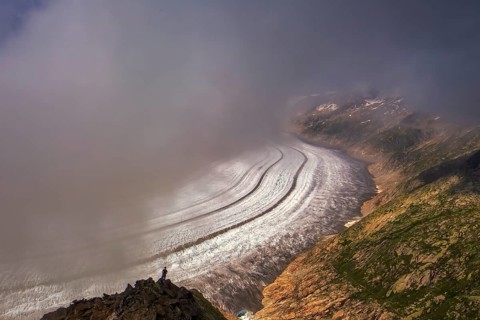 On a foggy day, a tourist observes the largest glacier in the Alps, the Aletsch Glacier, UNESCO