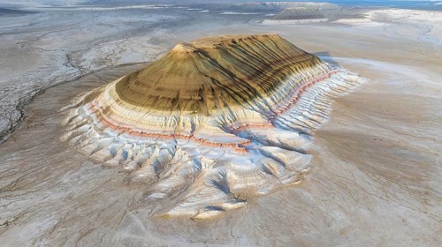 Aerial view of Mount Bokty, isolated sandstone mountain rising above the desert landscape,