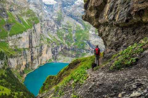 On a summer day, a tourist walks along the panoramic trail with views of Oeschinen Lake