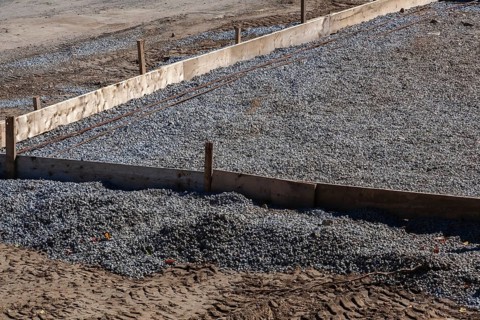 Wooden concrete pouring forms and bed of crushed and compacted stone aggregate to rest concrete