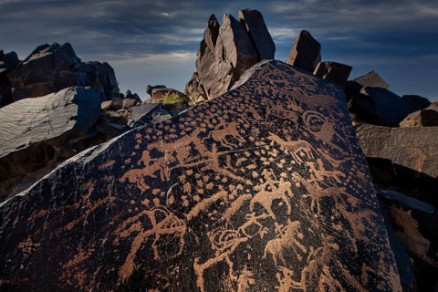 Ancient rock carvings of animals and human figures, depicting a hunting scene, dating from the