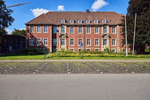 Town hall, brick buildings, flagpoles, façade with windows, dormers, parking boxes, sidewalk,