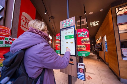 A woman interacts with an ordering machine in a modern fast food restaurant, London, England, Great