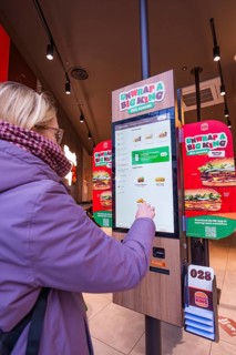 A woman uses an ordering machine in a modern burger restaurant, London, England, Great Britain