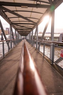 A modern metal footbridge stretches across a river in sunlight, London, England, Great Britain
