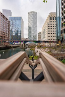 Modern buildings on a waterway with a bridge and sidewalks in the foreground, Canary Wharf, London,