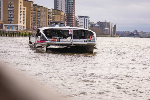 A river with tall modern buildings on its banks, with a ship in the foreground, London, England,