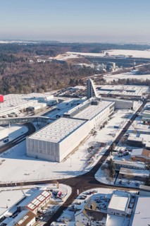 Snowy industrial area with forest in the background, characterized by clear lines and roads,