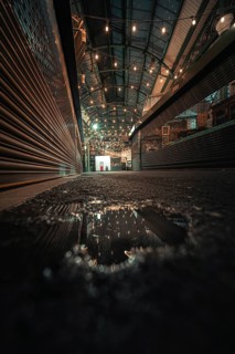 Puddle reflects lights in an urban canopy area at night, London, Borough Market, United Kingdom