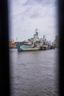 View between two structures of a ship in the river in front of historic towers, HMS Belfast,