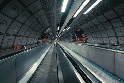 Long subway tunnel with escalator, symmetrical design and modern lighting, London, United Kingdom