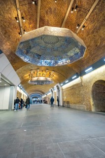Long tunnel with decorative ceiling and people, warm lighting in an urban setting, London Bridge