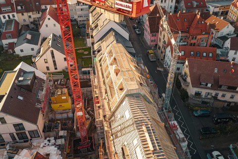 Upper perspective of a construction site in a residential area with visible roof structures,
