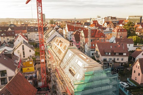Construction site on a roof in the city with crane and surrounding houses, carpentry, renovation,