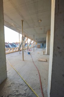 Open interior with construction work, exposed concrete walls and supports, carpentry construction