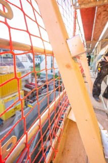 Close-up of a red safety net on scaffolding on a construction site, carpentry construction, roof