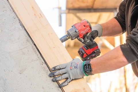 A worker with a cordless screwdriver fixing a piece of wood on a construction site, carpentry
