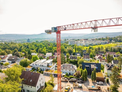 Crane over an urban residential area with green areas and a wide view, construction site of a